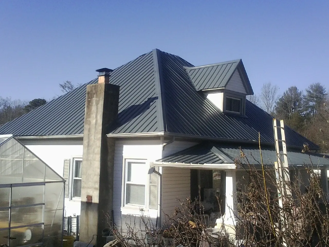 Dark blue standing seam metal roof on a white farmhouse with dormer — Slate & Tile Roof Repair by Roofing Brothers in Rydal
