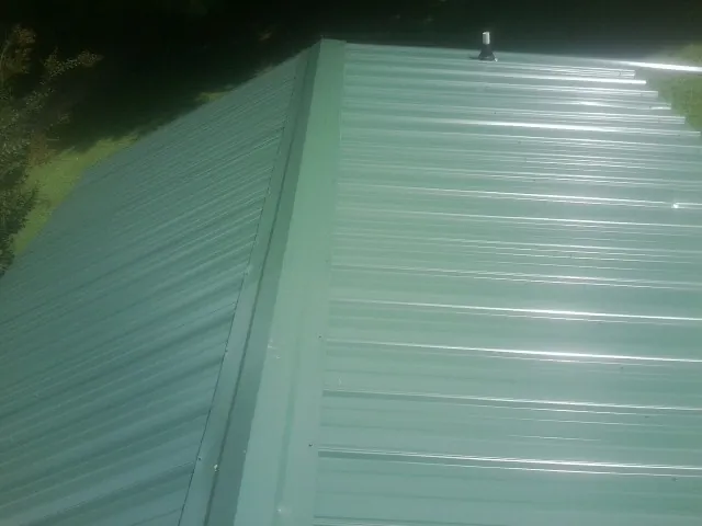 New green metal panels meeting at the ridge of a roof — Flat Roof Repair work by our crew in Rydal