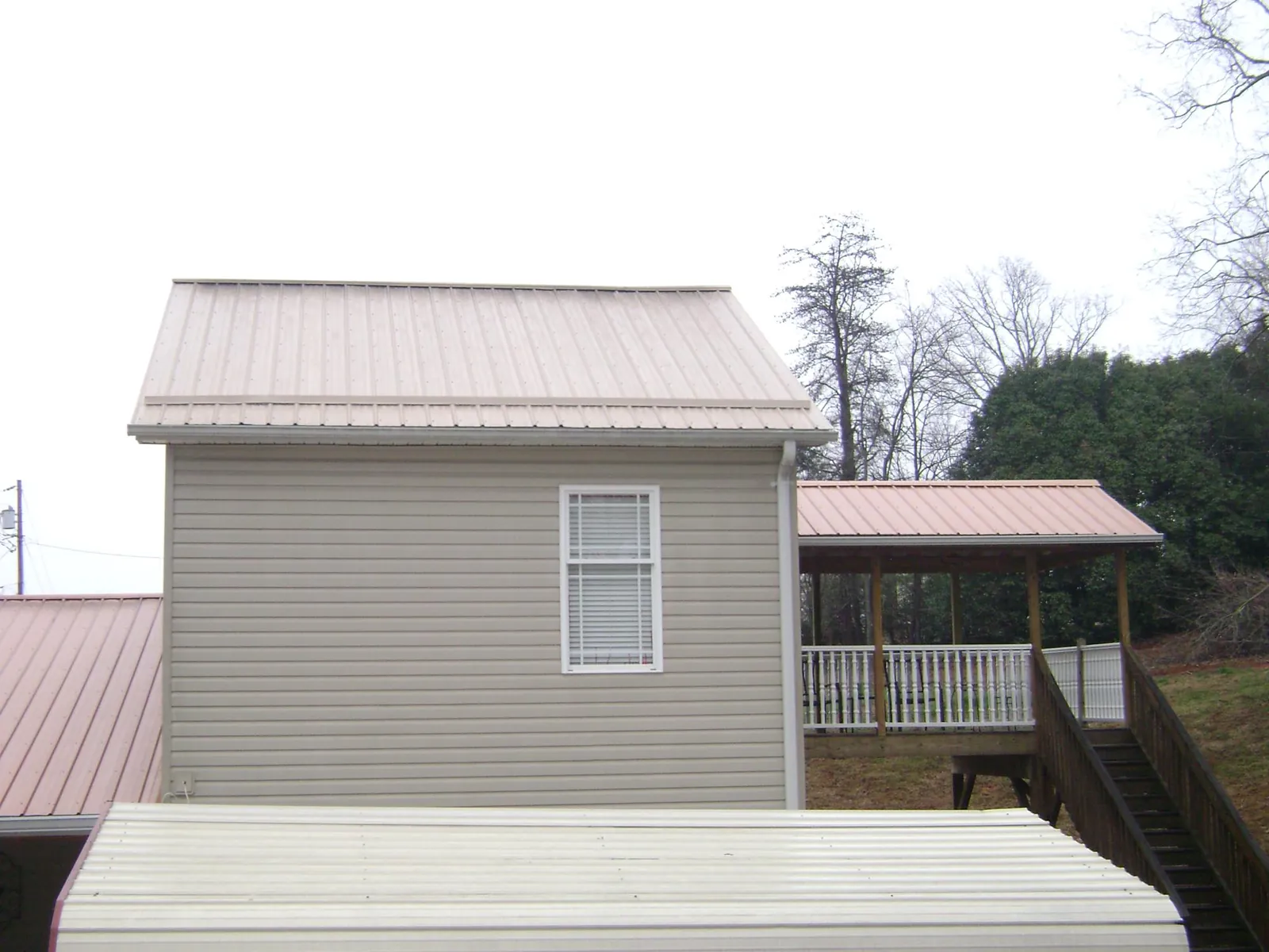 Tan metal roofs on a two story addition and attached porch, from a Roof Replacement job in Rydal